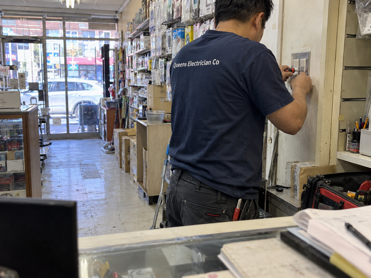 Queens Electrician Co electrician at work in a Flushing storefront